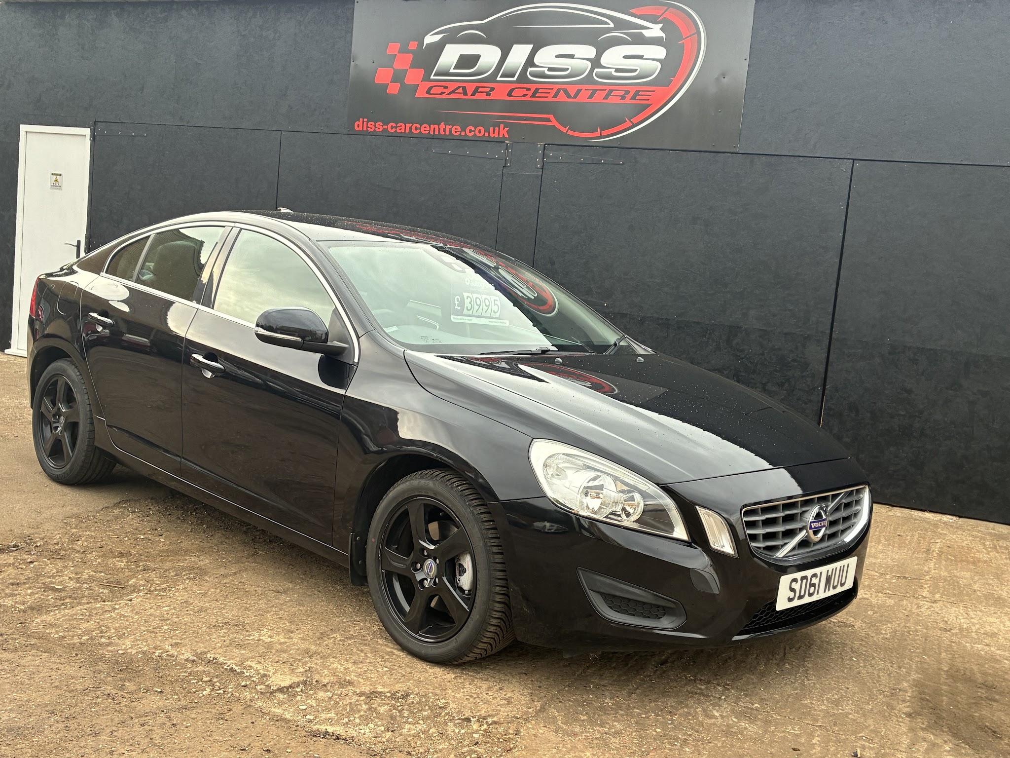 Black Volvo S60 saloon on the forecourt in front of the Diss Car Centre sign