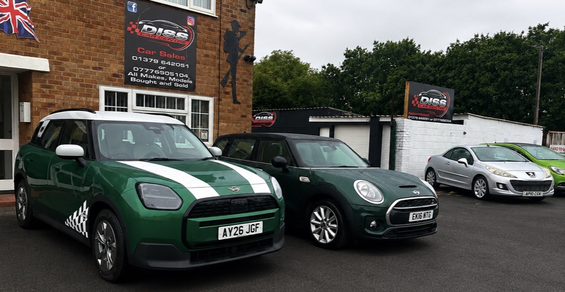 The Diss Car Centre building on Mission Road with its Car Sales sign, two green MINIs parked outside